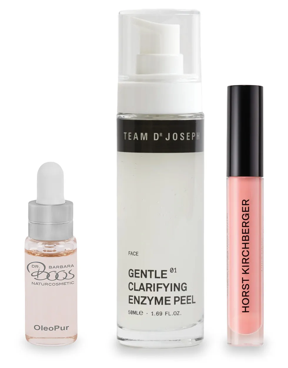 Drei Kosmetikprodukte stehen nebeneinander. Links ein kleines Fläschchen mit Pipette, in der Mitte ein größeres Fläschchen mit Pumpspender, rechts ein dünnes Röhrchen mit Applikator. Alle Behälter sind durchsichtig mit Etiketten.